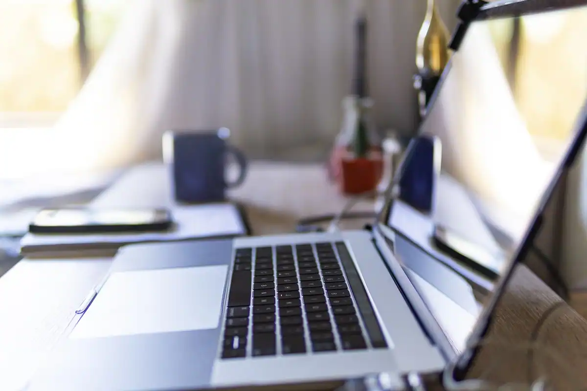 Laptop deschis pe un birou, lângă o cană, într-un colț de lucru pentru blog