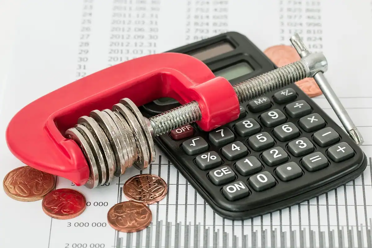 Menghină roșie care strânge monede, lângă un calculator de birou