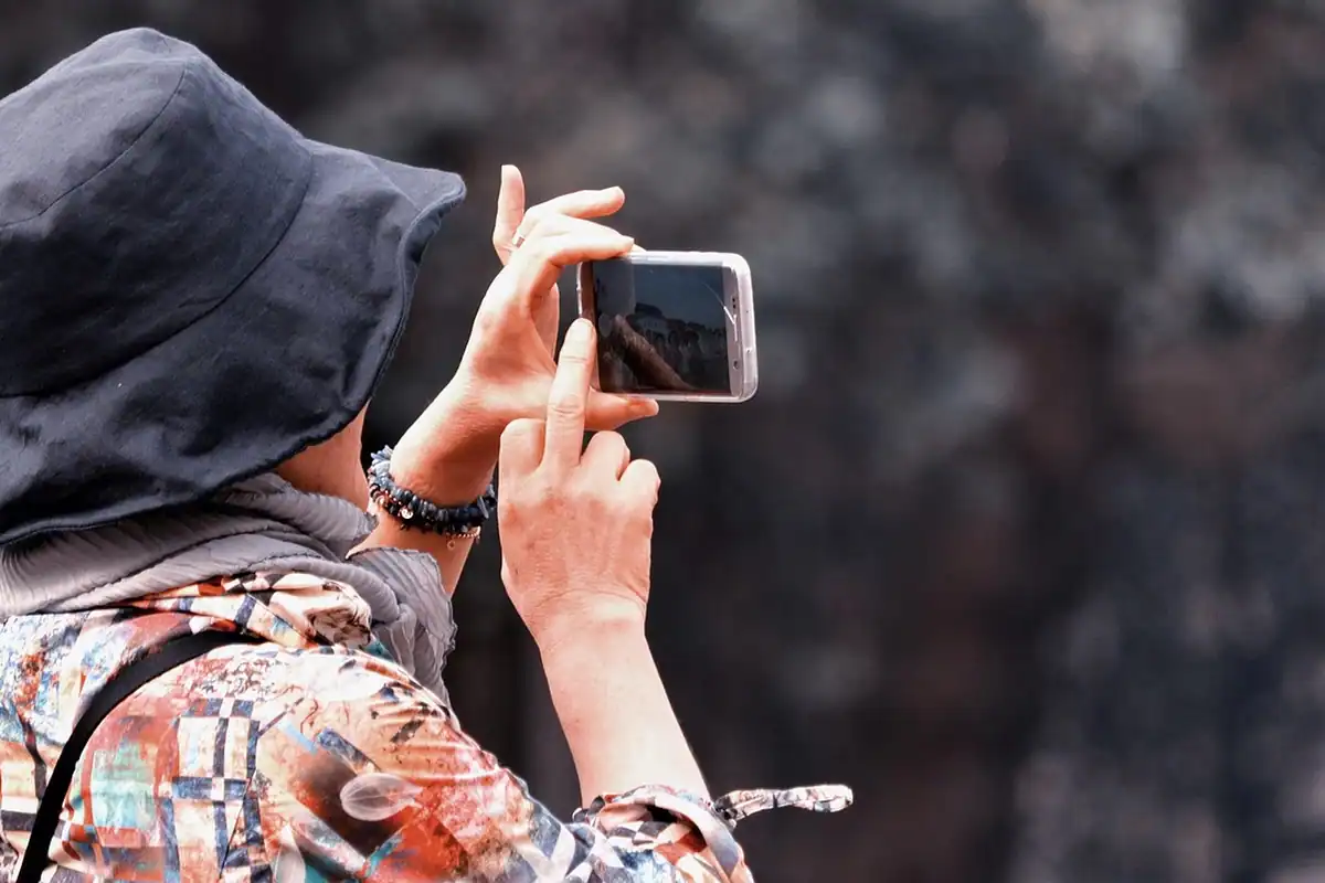 Mâini care țin un smartphone și fotografiază un produs, pentru fotografii cu telefonul pe social media