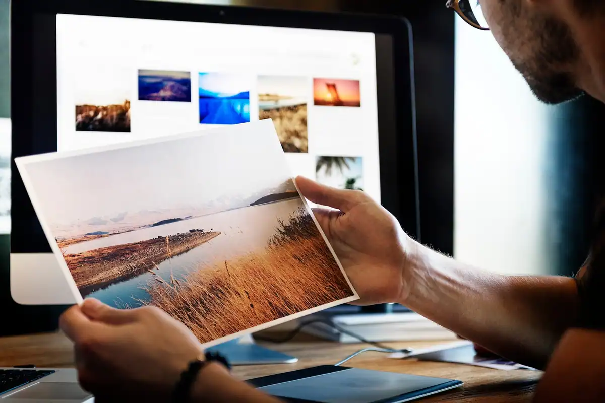 Fotograf care editează poze pe un monitor, pregătirea imaginilor pentru SEO