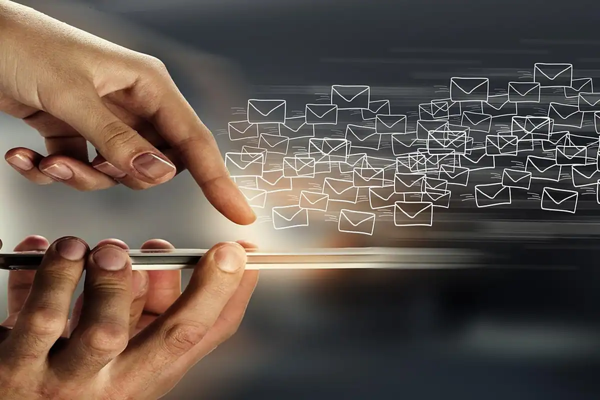 Mână care ține un telefon din care ies plicuri de e-mail