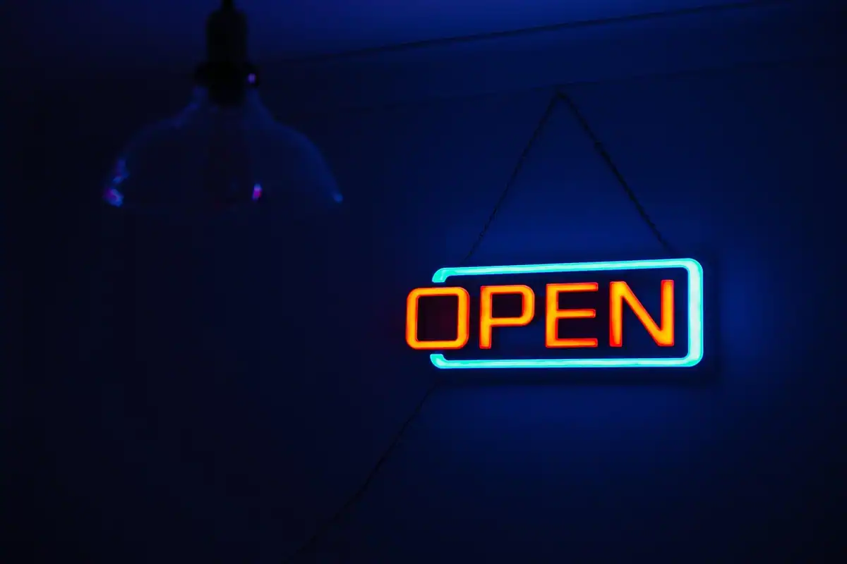 Reclamă luminoasă cu neon și cuvântul OPEN pe fundal albastru închis