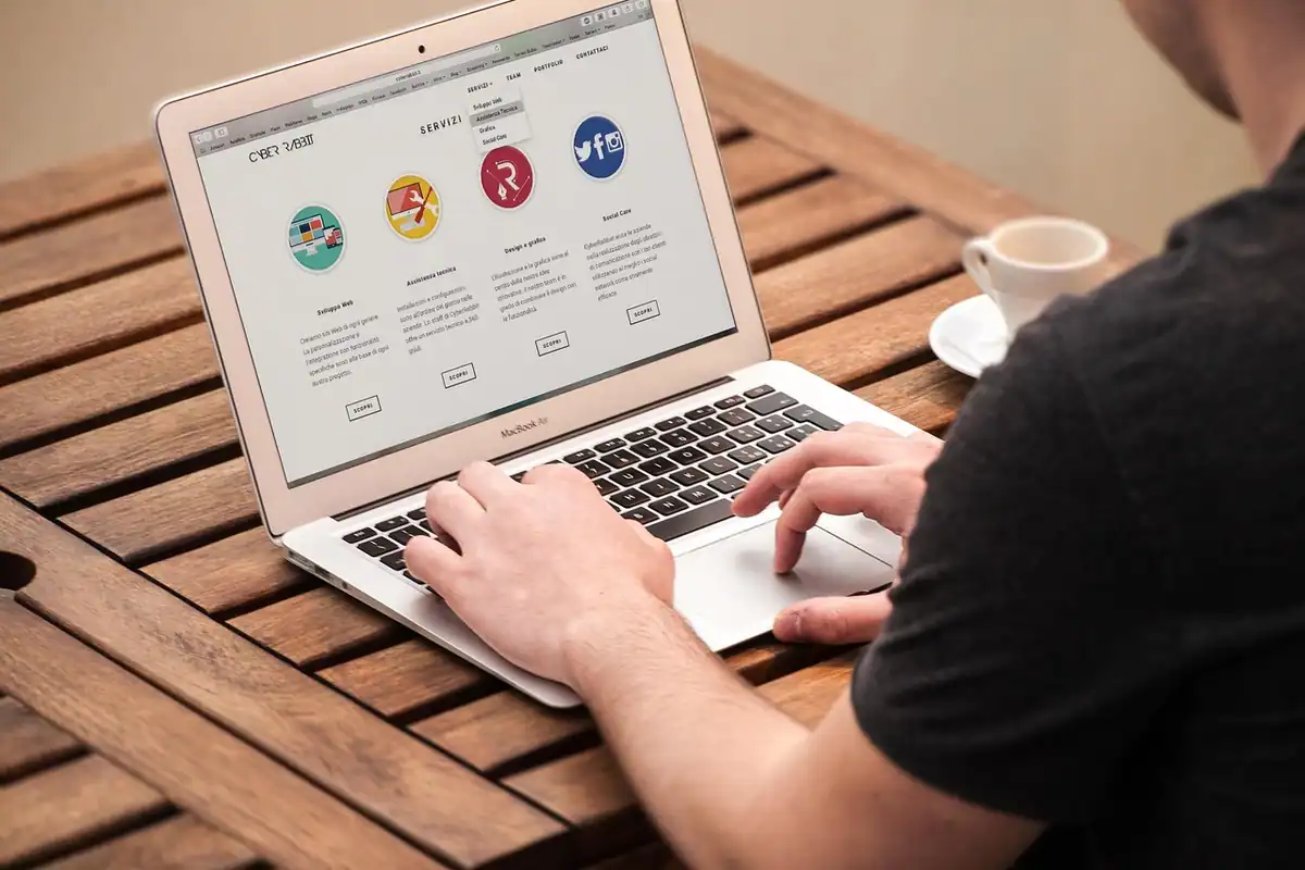Bărbat care tastează pe un laptop cu o pagină web cu iconițe