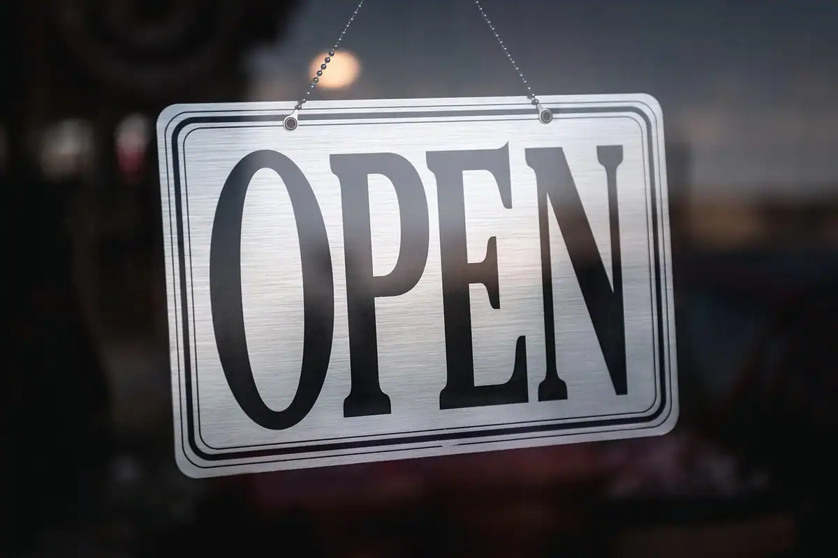 Tăbliță cu inscripția OPEN atârnată în ușa unui magazin