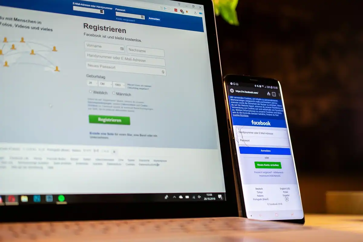 Laptop și telefon care afișează pagina de înregistrare Facebook