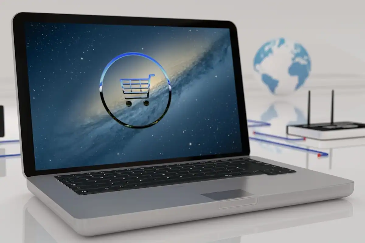 Laptop cu o pictogramă de coș de cumpărături pe ecran, lângă un glob
