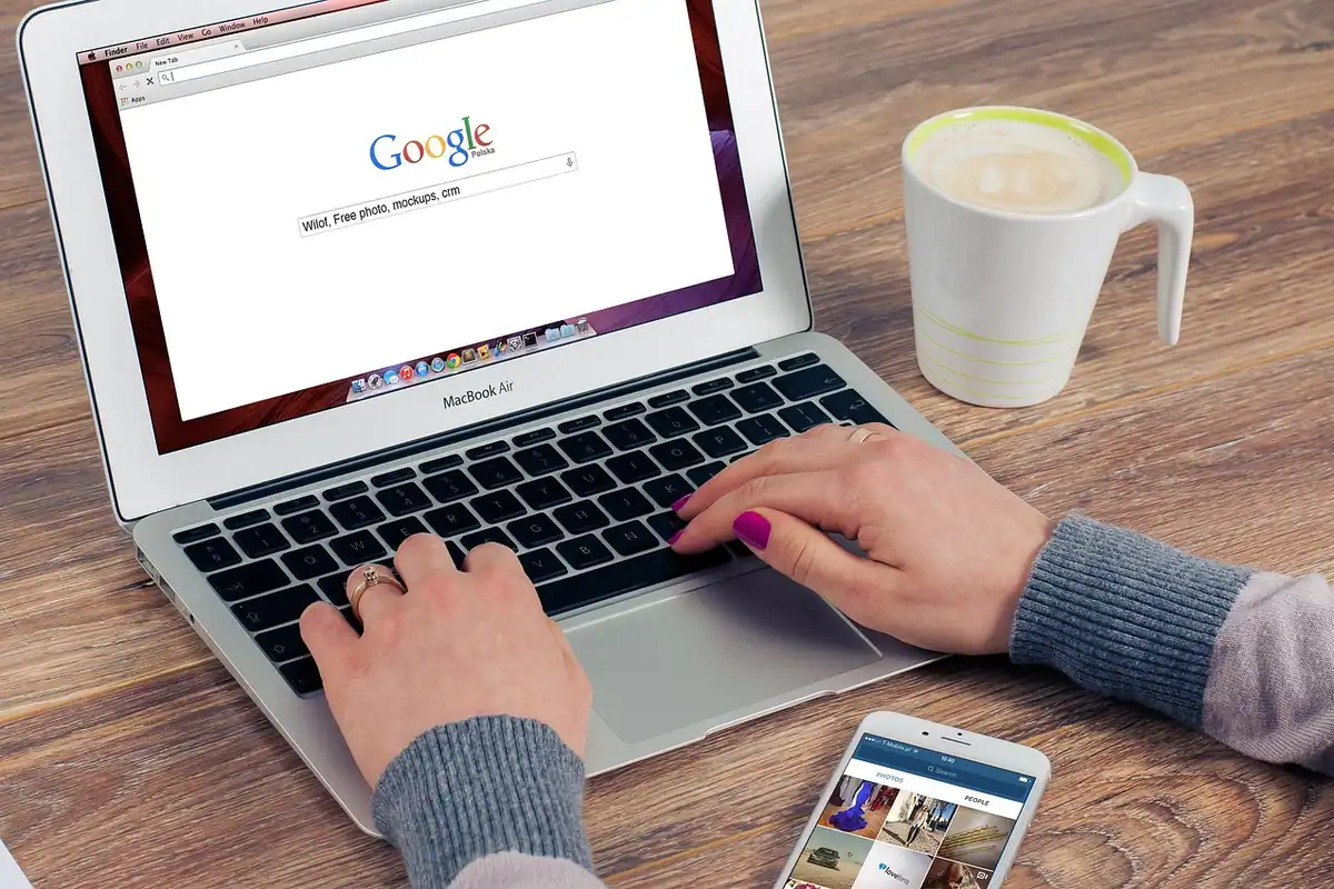 Laptop cu pagina Google deschisă, lângă o cană cu cafea