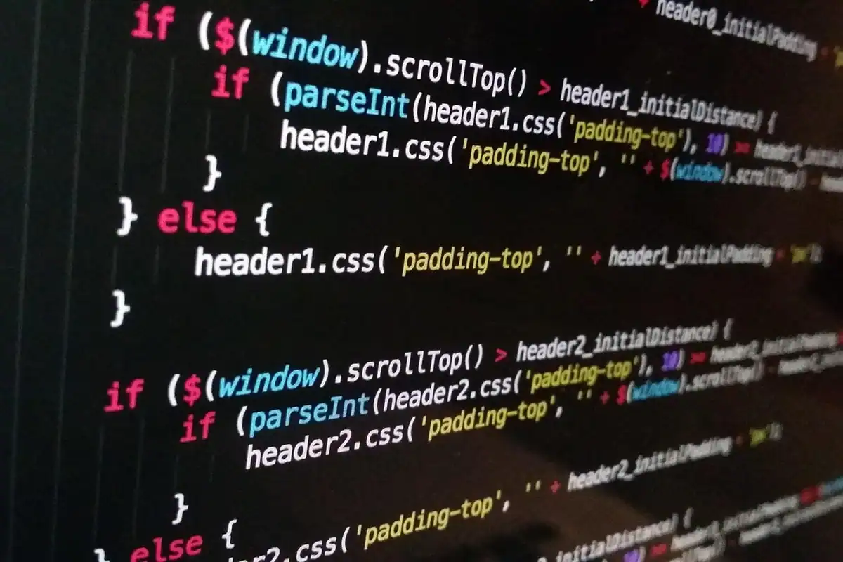 Cod JavaScript afișat pe un ecran negru, cu litere colorate