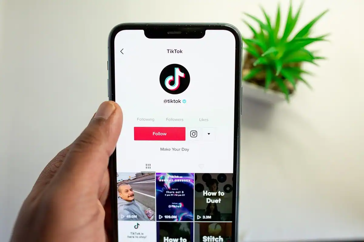 Mână care ține un telefon cu profilul unui cont TikTok deschis