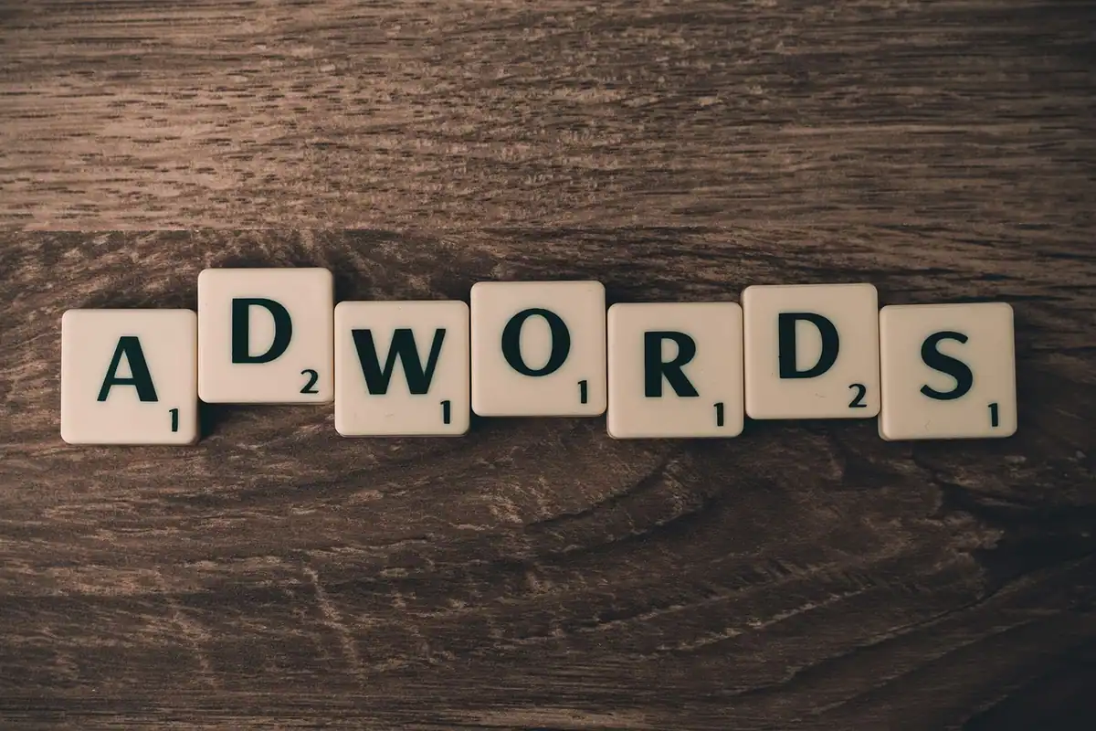 Piese de joc care formează cuvântul AdWords pe o masă de lemn